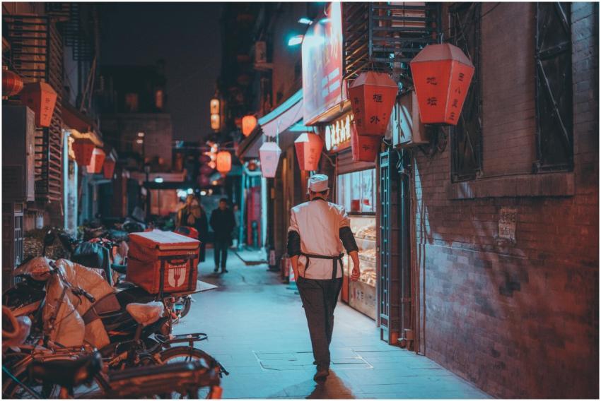 A chef in white uniform walking down a lantern-lit