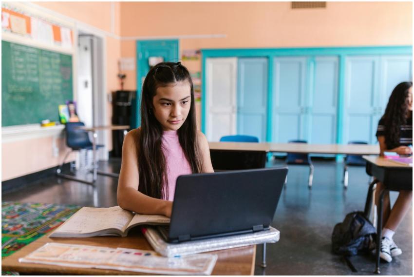 A focused young girl using a laptop for schoolwork