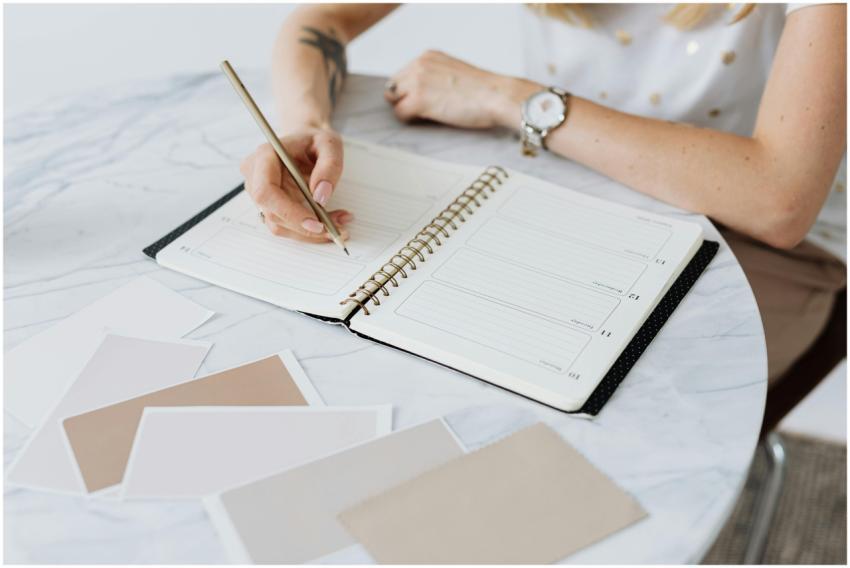 A woman writes in a planner on a marble table, sur