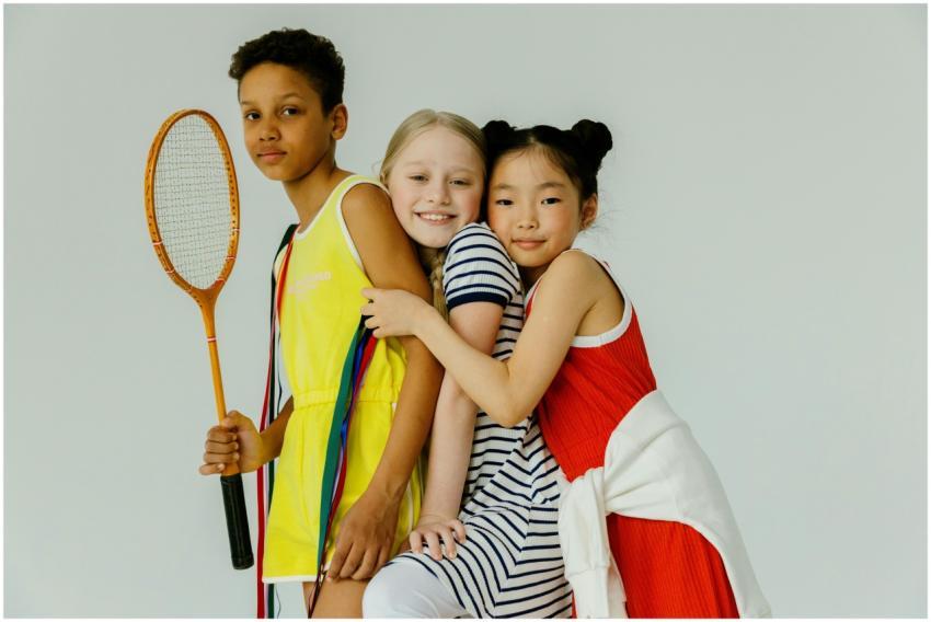 Three diverse children posing together with a tenn