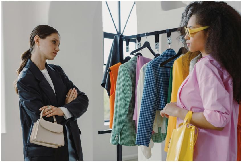 Two women browsing colorful clothing racks in a mo