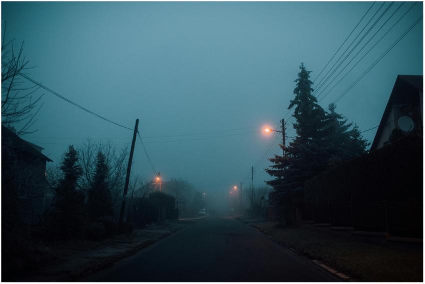 A foggy suburban street with street lights illumin