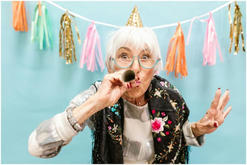 Elderly woman with eyeglasses and party hat celebr