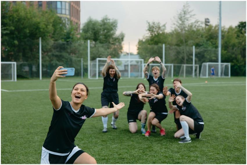 A women's soccer team takes a joyful group selfie