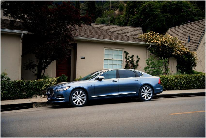 A sleek blue luxury car parked in front of a subur