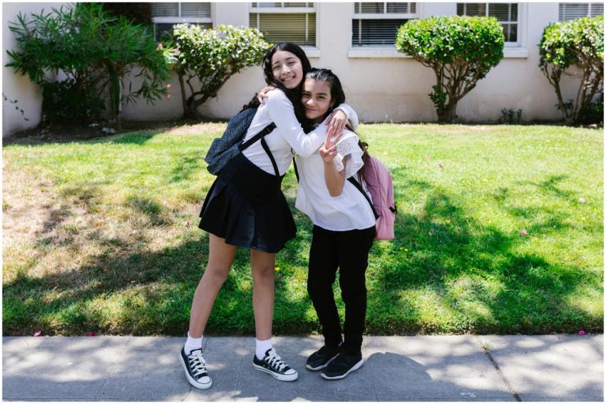 Two friends hugging outside a school building on a