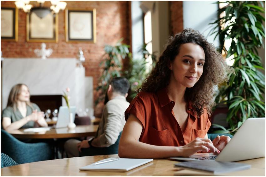 Woman in a red shirt working on a laptop in a cozy
