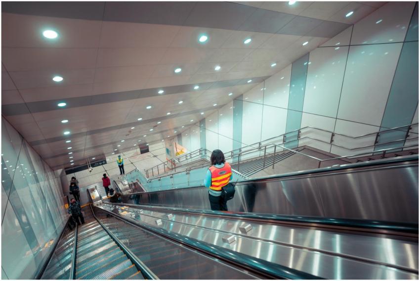 A modern subway station features people on escalat