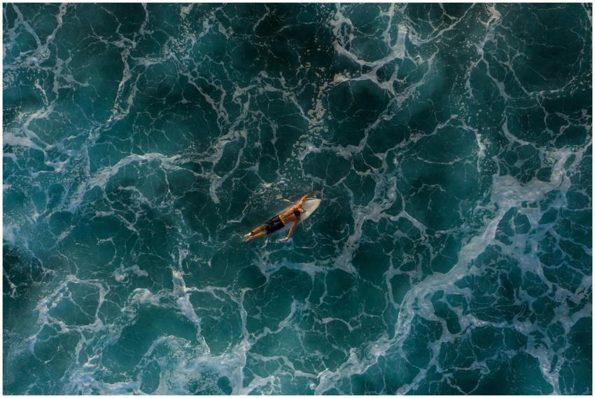 An aerial shot capturing a lone surfer navigating