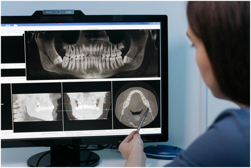 A dentist examines dental X-rays on a computer scr