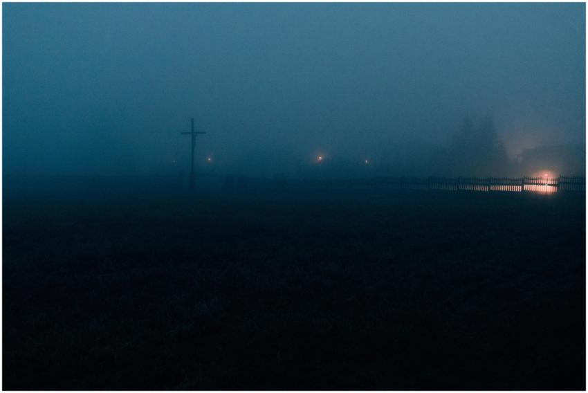 Eerie night landscape with fog, faint lights, and