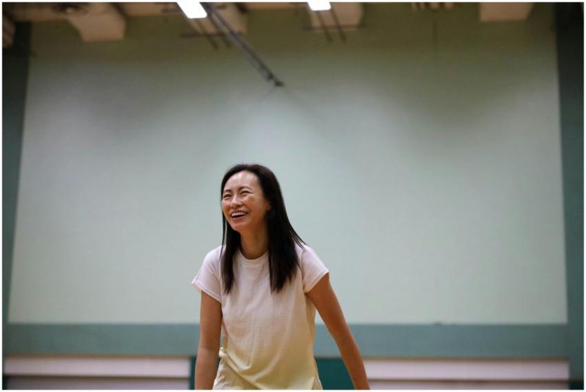 A cheerful woman enjoys playing badminton indoors,