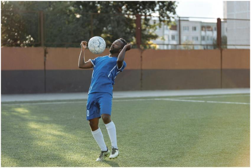 Athlete in blue uniform skillfully heads the socce