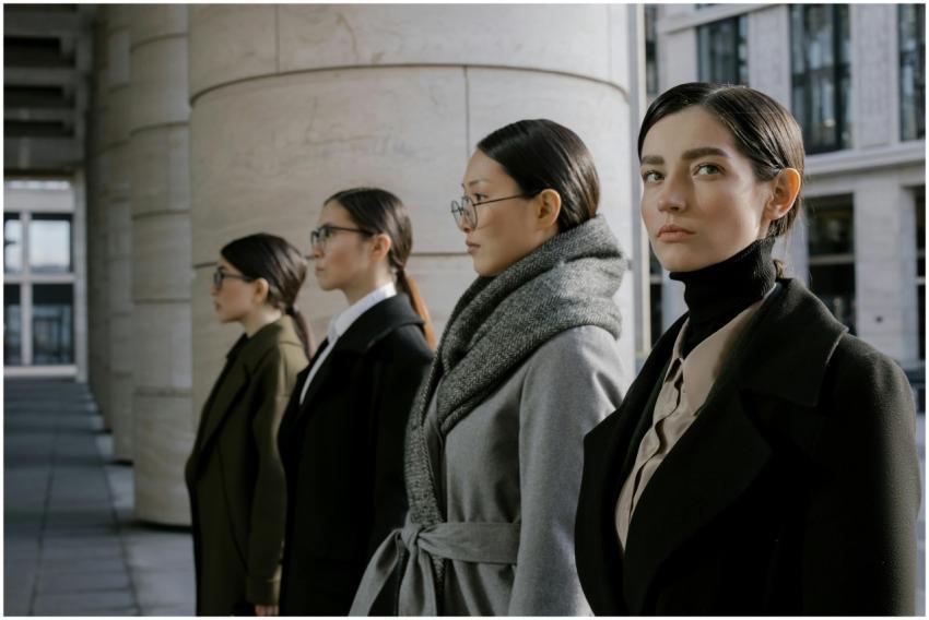 Four professional women in elegant coats walking i