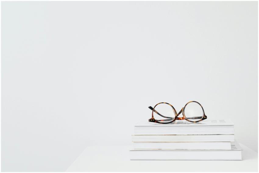Eyeglasses on stacked books against a clean white