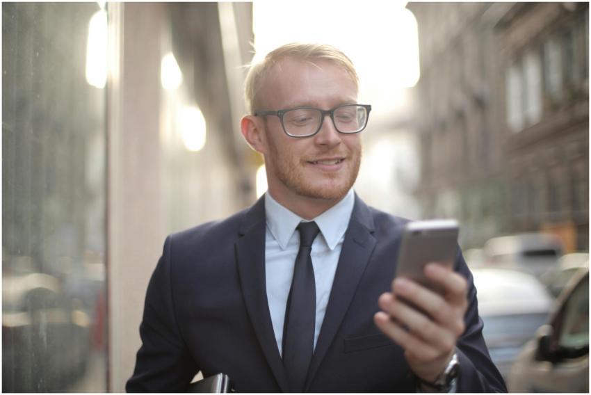 Smiling businessman in a suit using a smartphone o