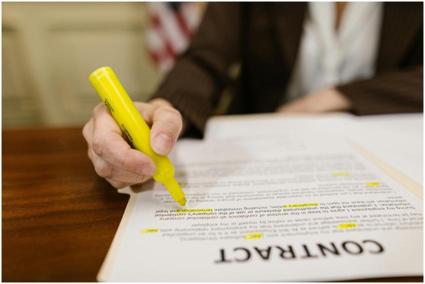 A close-up of a hand highlighting a contract, emph