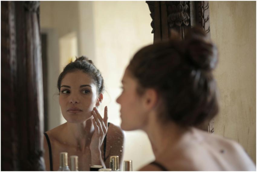 A woman checks her skin in the mirror, engaging in