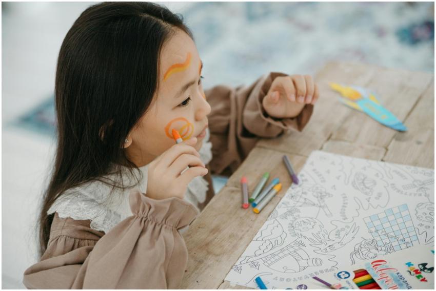 Young girl having fun with face painting and drawi