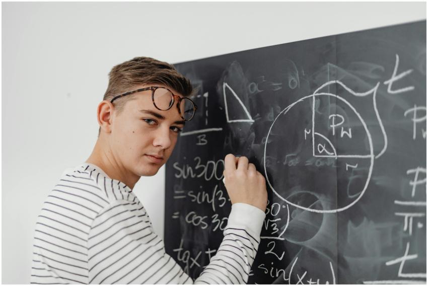 A teenager writes mathematical equations on a blac