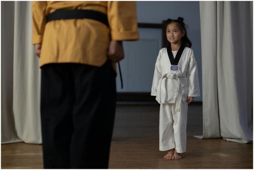 Young girl standing in martial arts uniform facing
