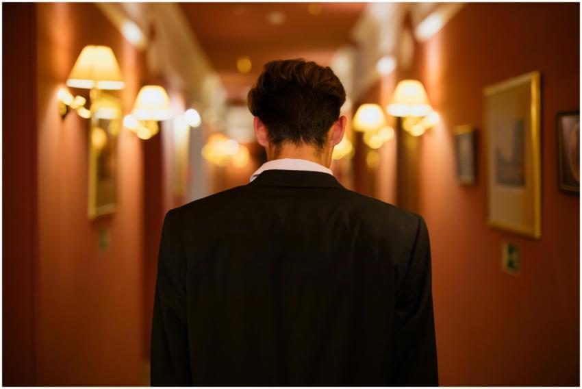 Rear view of man in black suit walking down a warm