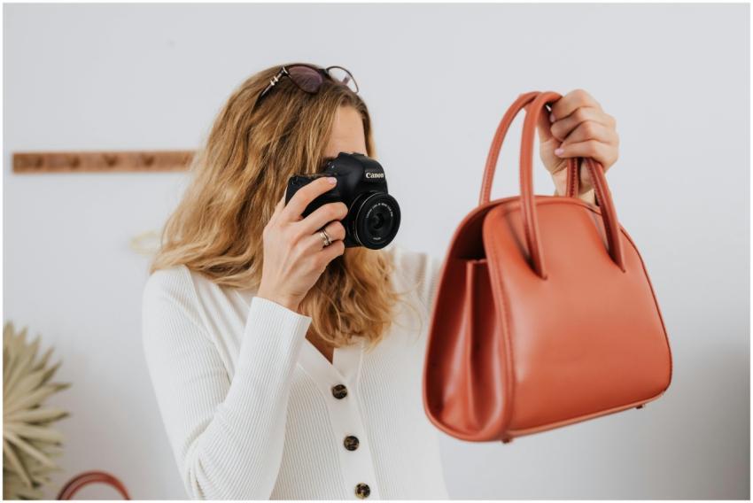 A woman in white long sleeves photographs a handba