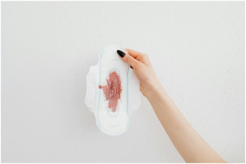 A close-up image of a hand holding a menstrual pad