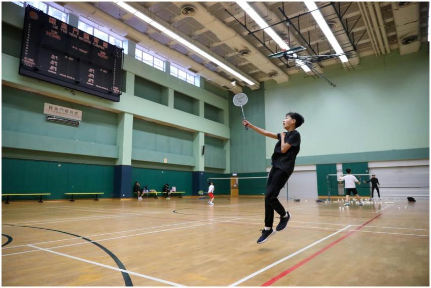 A young athlete in motion playing badminton in a s