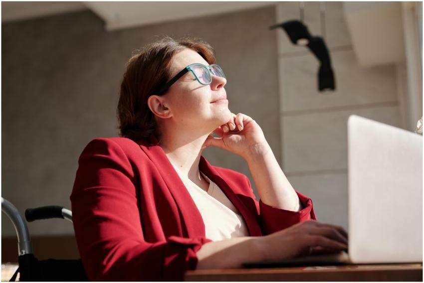 Woman in wheelchair wearing red suit and glasses,