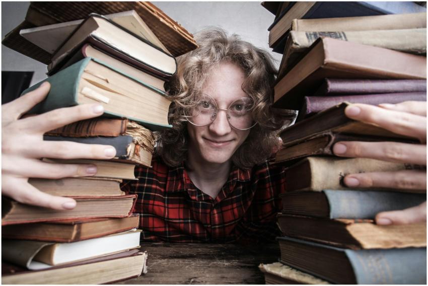 A young man in glasses surrounded by stacks of vin