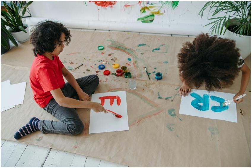Two children painting with watercolors on paper, e