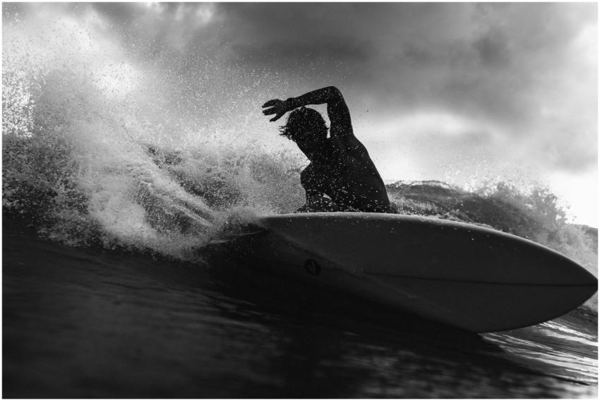 Black and white of anonymous male surfer riding on