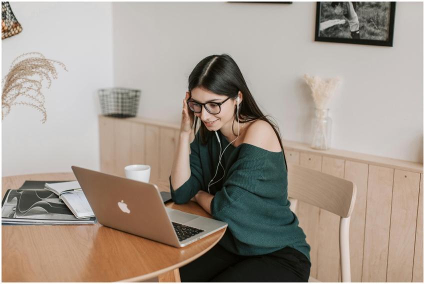 Smiling woman using laptop and earbuds for online