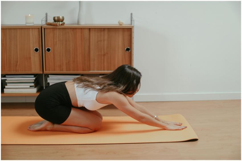 A woman performing yoga indoors on an orange mat,