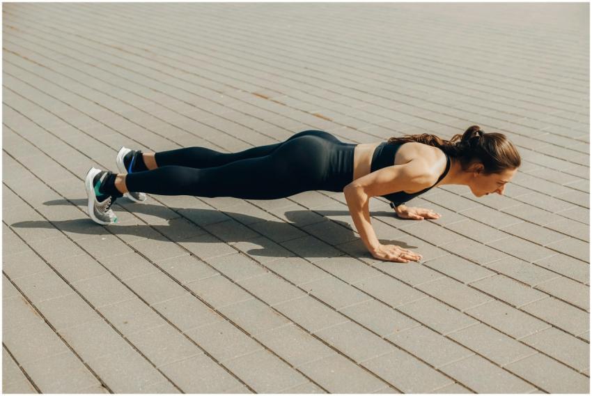 Woman performing a push-up exercise outdoors in sp