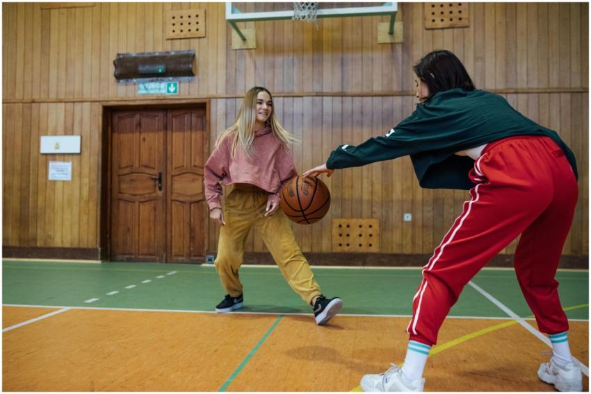 Two young women playing basketball indoors in casu