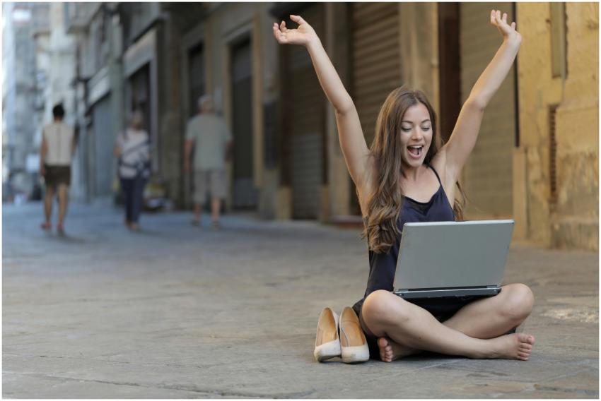 A cheerful woman sitting outdoors, celebrating suc