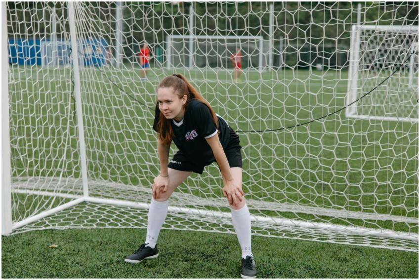 A focused female soccer player stands ready in the