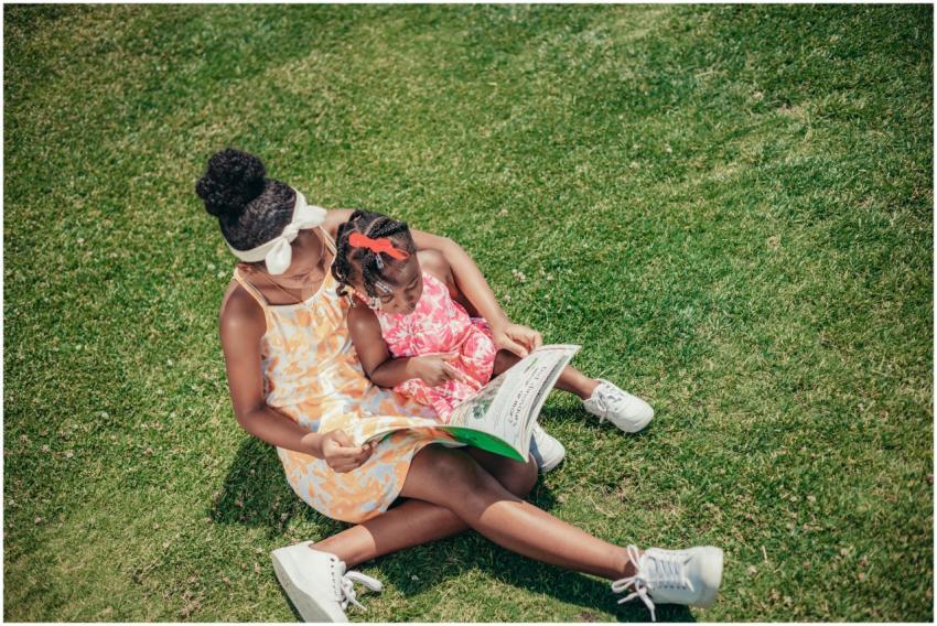 Two young sisters enjoy reading together on a sunn