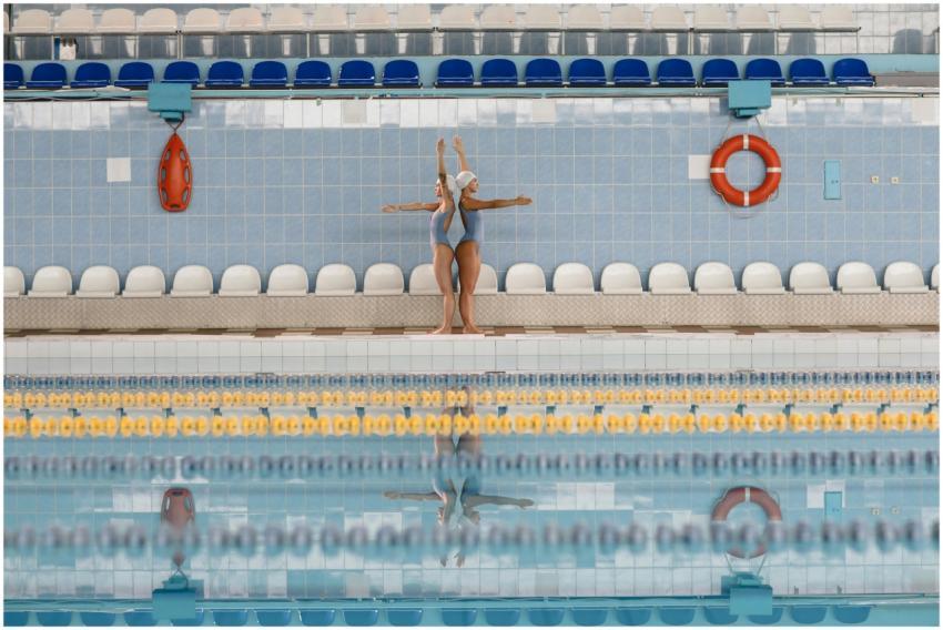 Two synchronized swimmers practice by the poolside