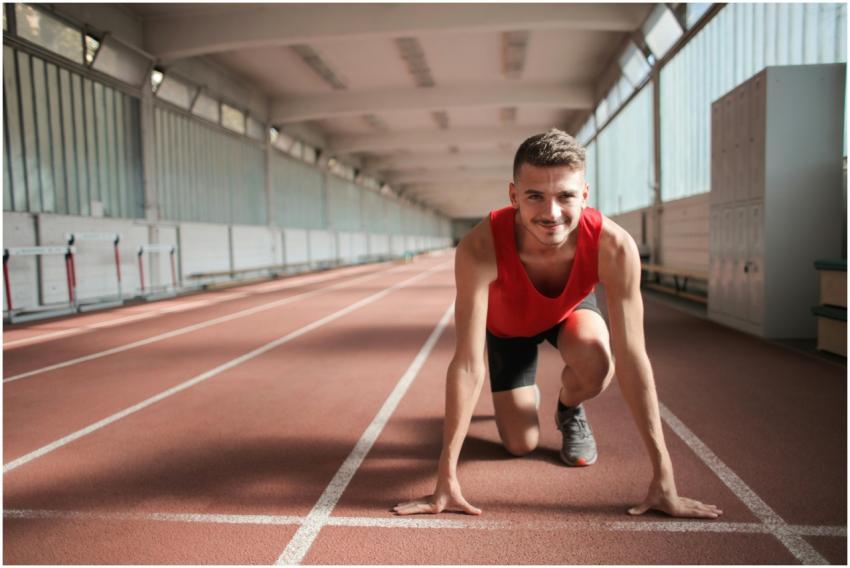 Male athlete in red top preparing for a sprint on
