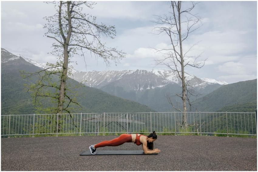 A woman doing a plank exercise on a mat outdoors w