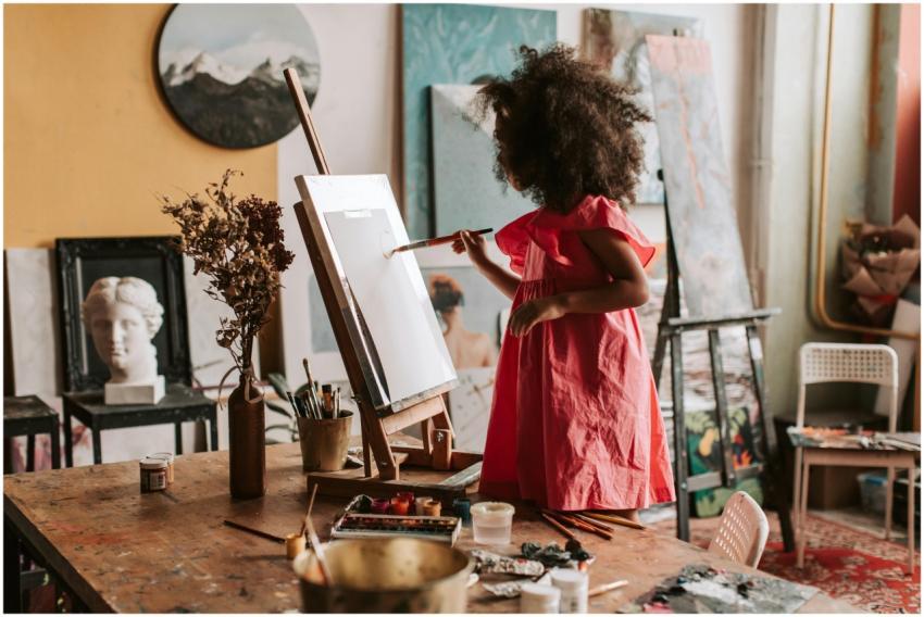 A young girl painting on a canvas in a cozy art st