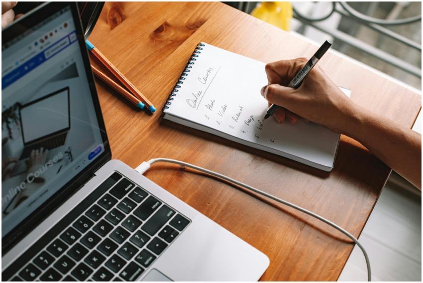 A person writing notes while researching online co