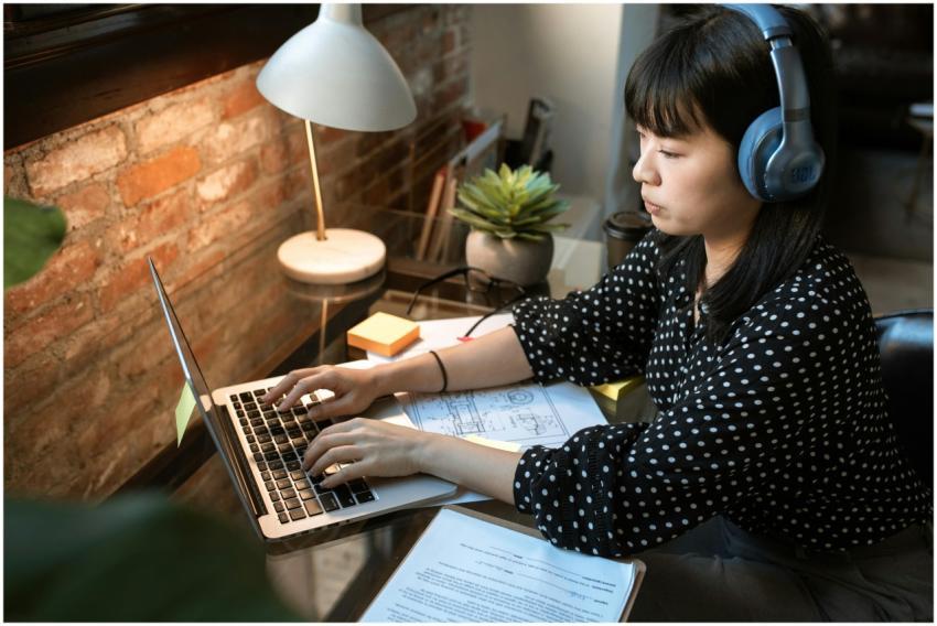 Focused woman wearing headphones, working on a lap