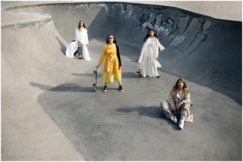 Stylish women in trendy outfits posing with skateb