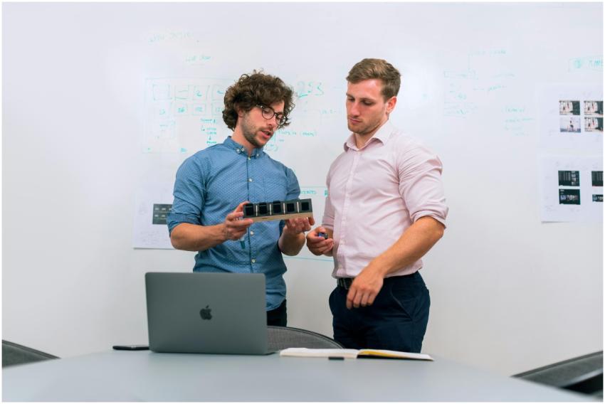 Two men in an office discussing and reviewing a te