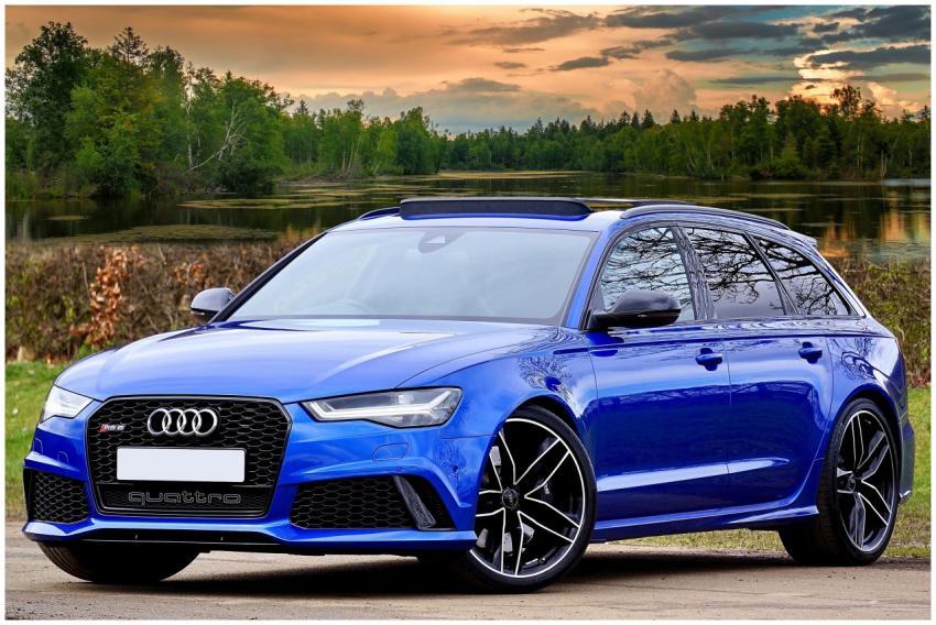 A modern blue Audi RS6 parked by a lake with sceni