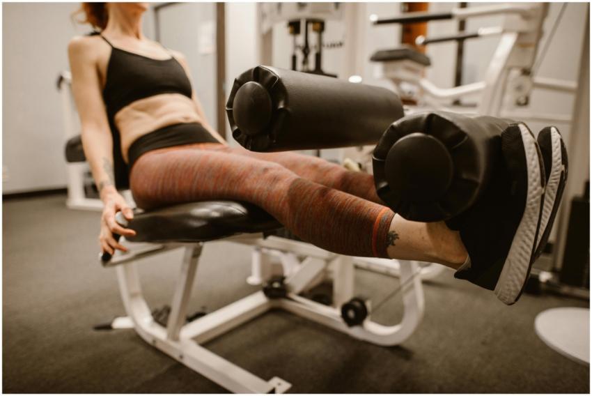 Focused woman exercising on leg curl machine in a